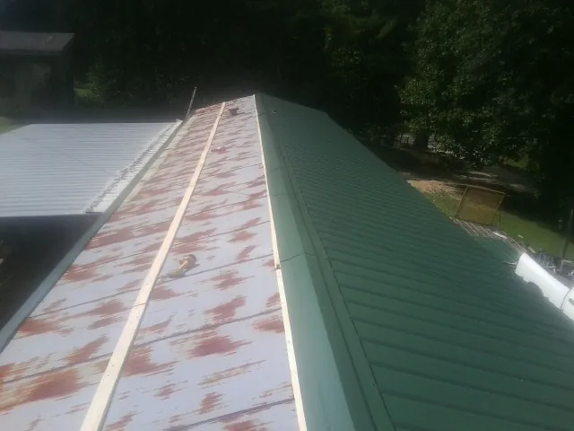 Old rusted panels beside newly installed green metal roofing — Wind Damage Roof Repair by Roofing Brothers in Laurens