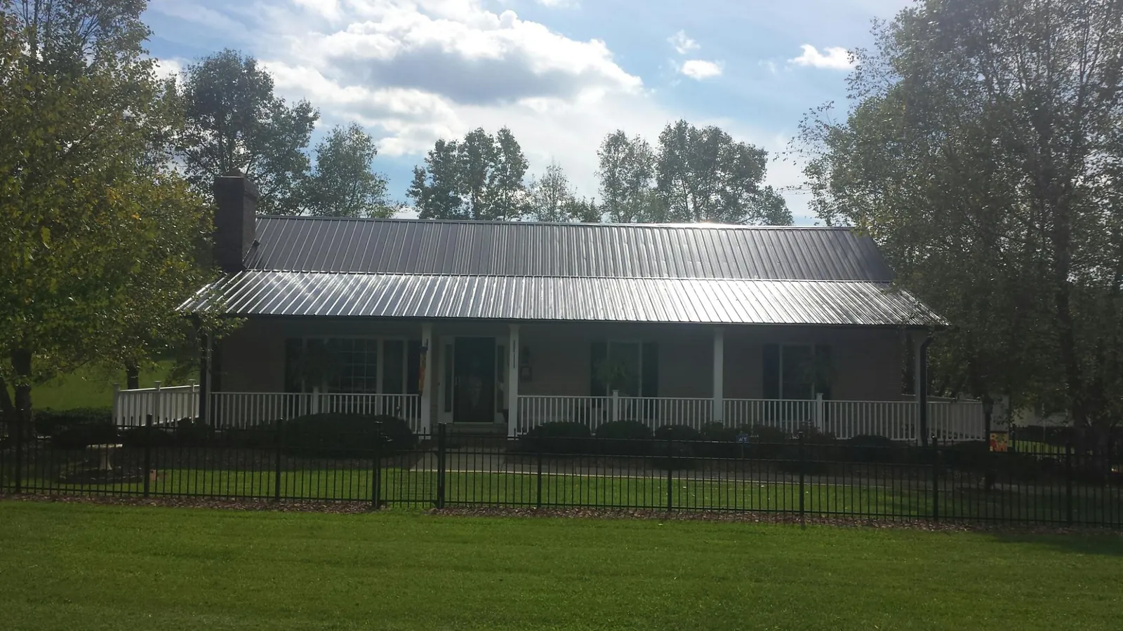 Gray metal roof on a brick ranch with a full width front porch — Gutter Guard Installation work by our crew in Laurens