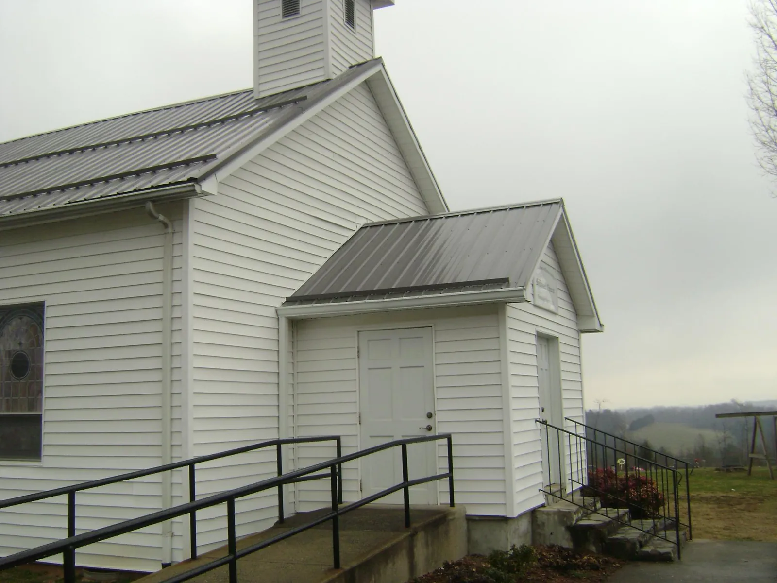 Gray metal roof on a white clapboard church with a steeple in Laurens